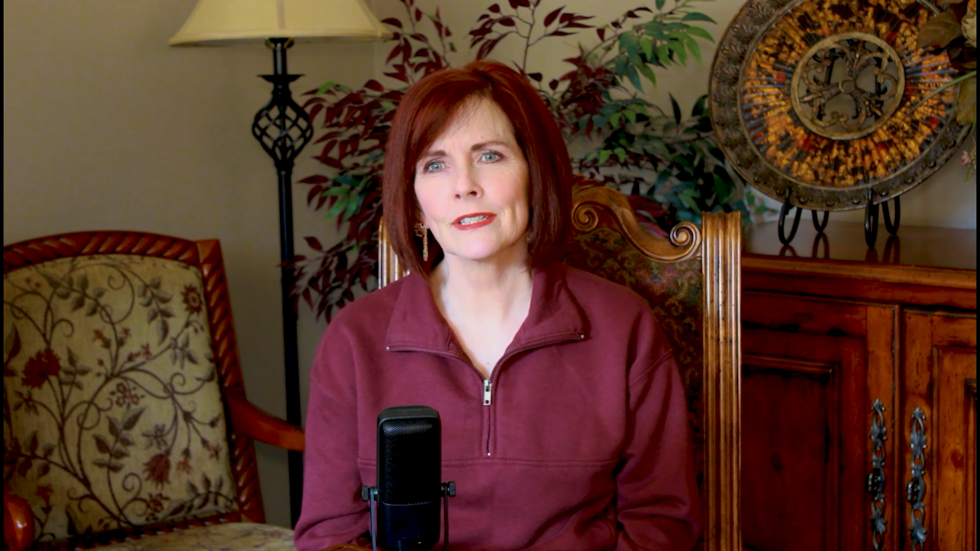Cofounder Leslee in a maroon sweater sitting in a room with decorative elements telling stories about her life. 