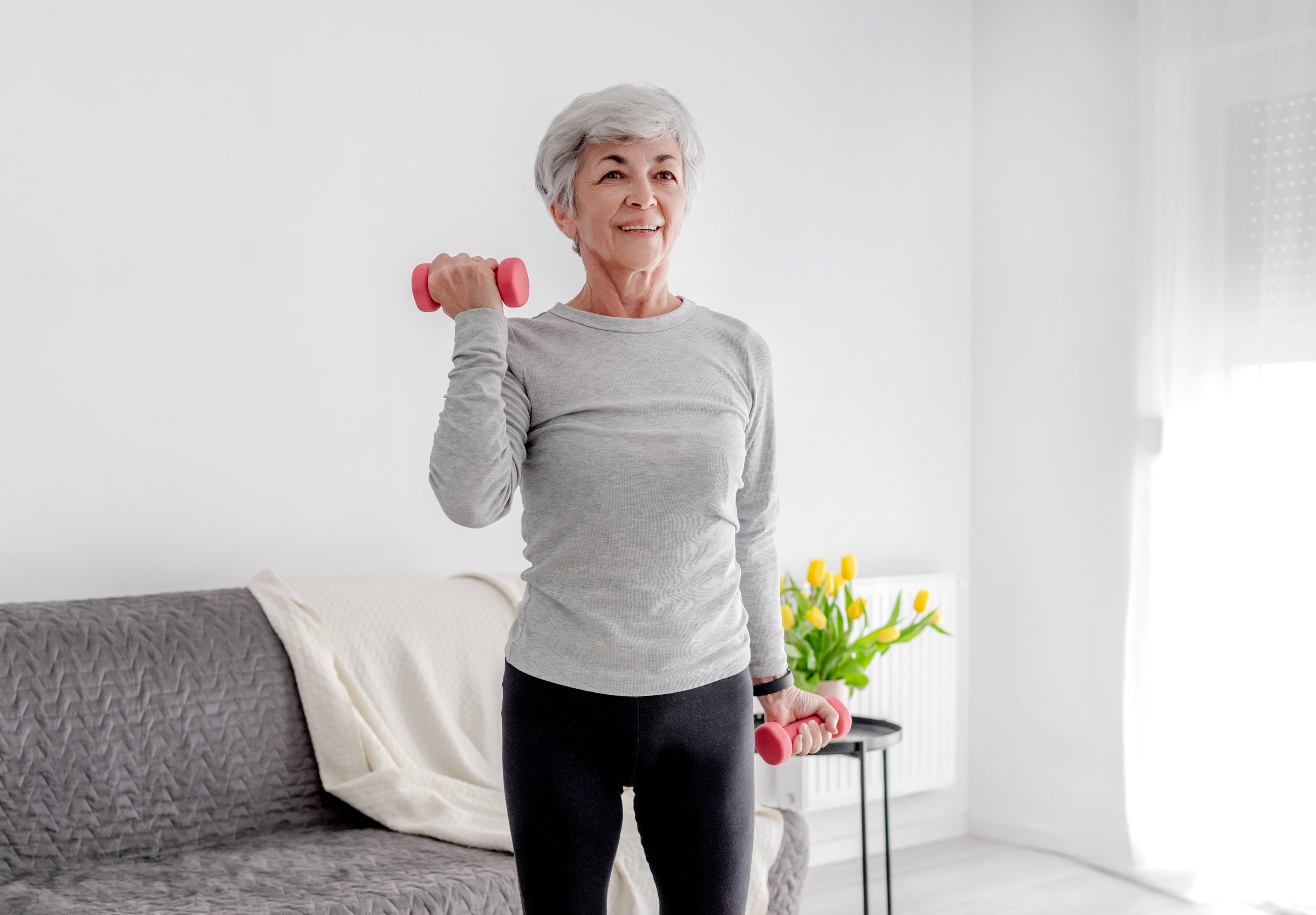 elderly woman lifting weights in her living room